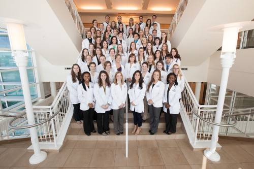 A Group photo taken of BSN students at the CHS building in Grand Rapids. There is a group of around 40 students, wearing white jackets arranged on a staircase and facing the camera.